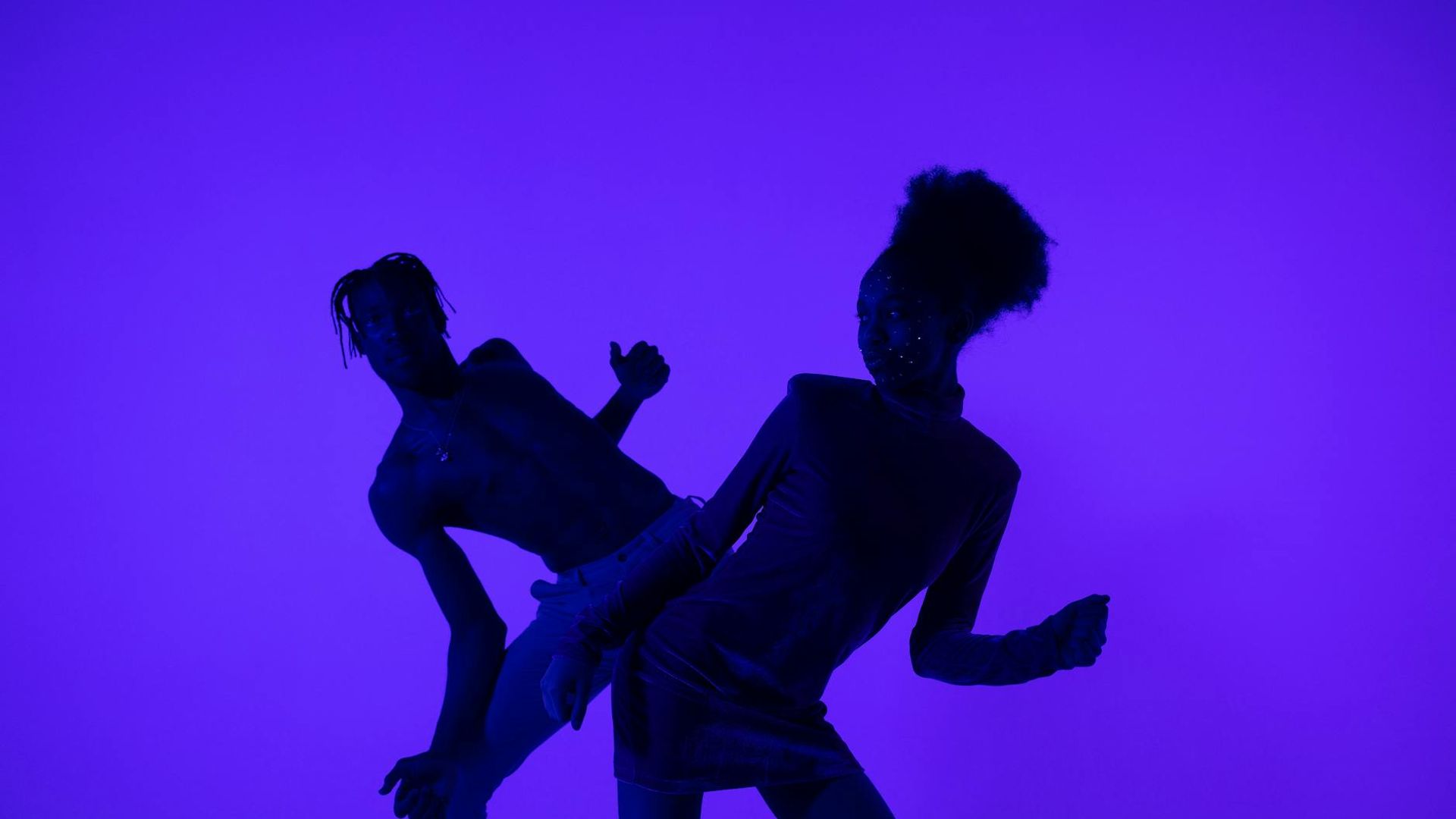 Person moving dynamically in a dark studio with neon lights.